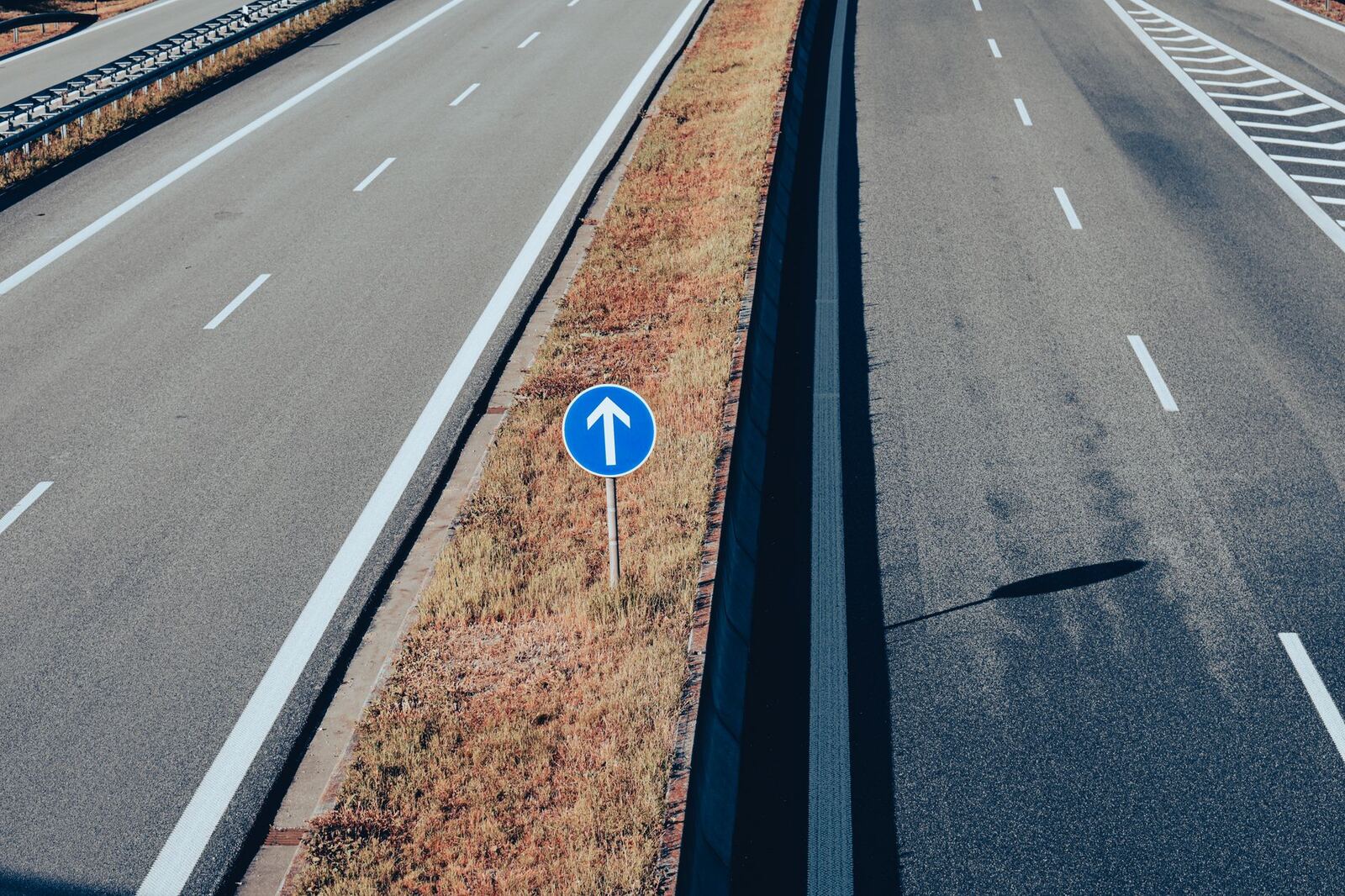 Aerial view of an empty highway highlighting a traffic sign with an arrow, emphasizing direction and transportation infrastructure.